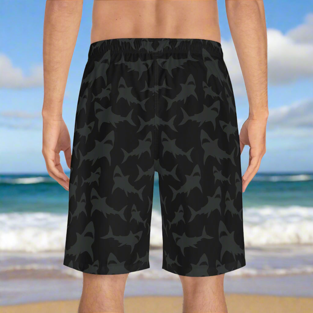 Man in bathing trunks with cool grey sharks printed pattern standing on the beach in Oahu waiting for high tide