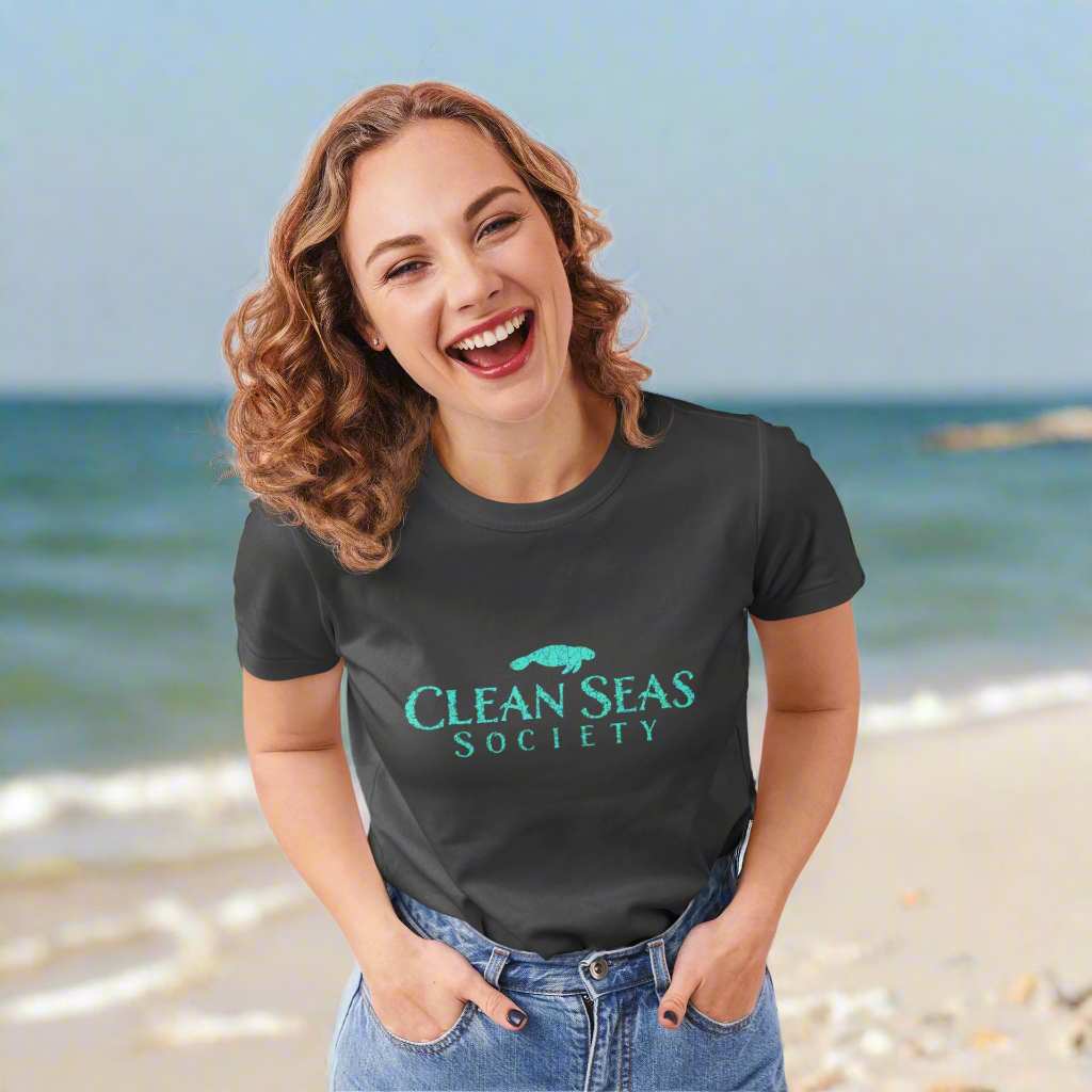 Woman wearing a dark heather gray  t-shirt with 'Clean Seas Society' logo at a local beach cleaning party
