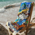 Mr. Fin Beach Towel draped over a wooden deck chair next to ocean waves.