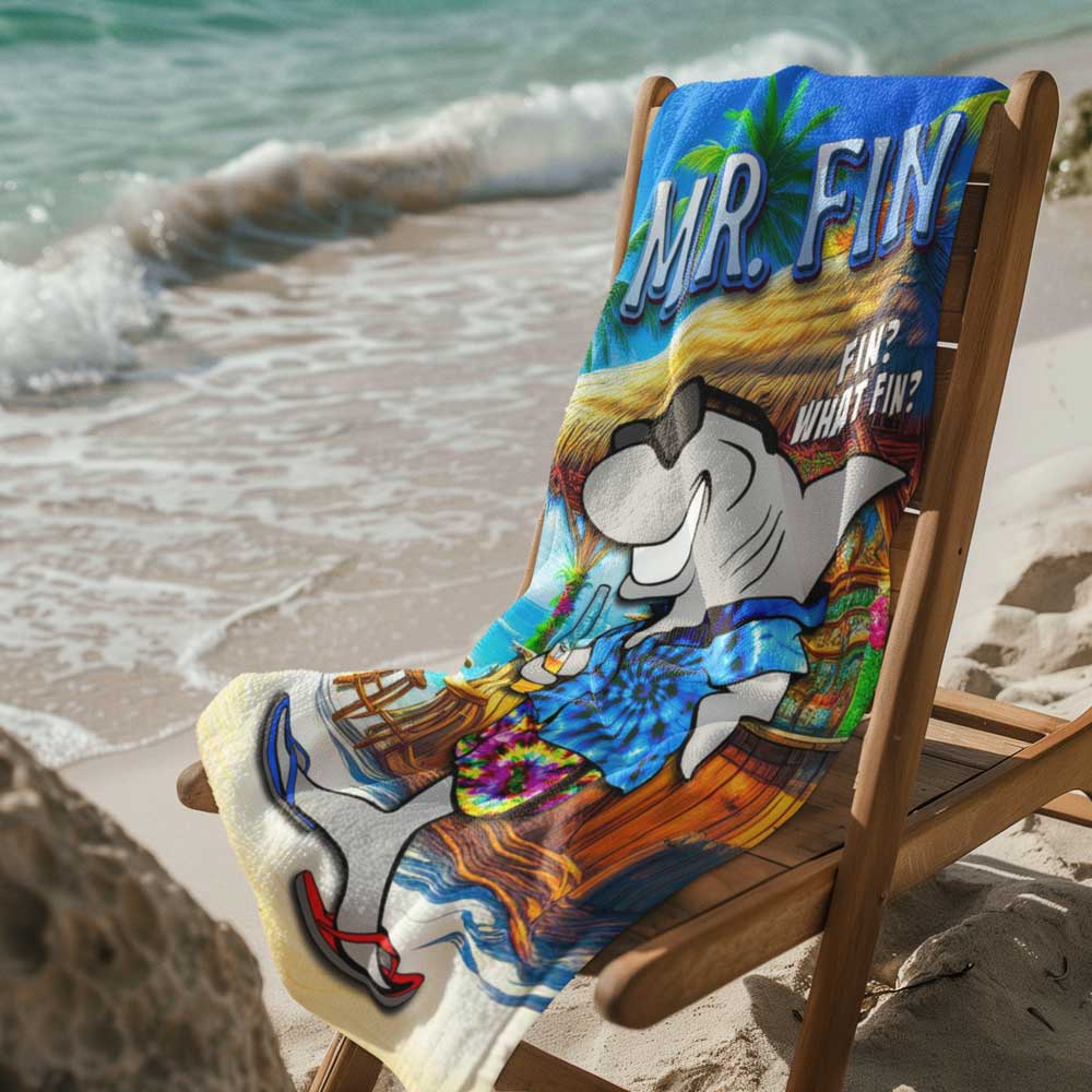 Mr. Fin Beach Towel draped over a wooden deck chair next to ocean waves.