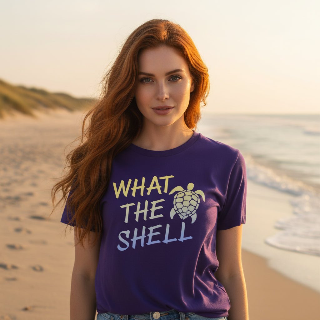 Beachwear model wearing A purple short-sleeve t-shirt  that features a graphic on the front with the text 'WHAT THE SHELL' in yellow and light blue, accompanied by a yellow sea turtle illustration.