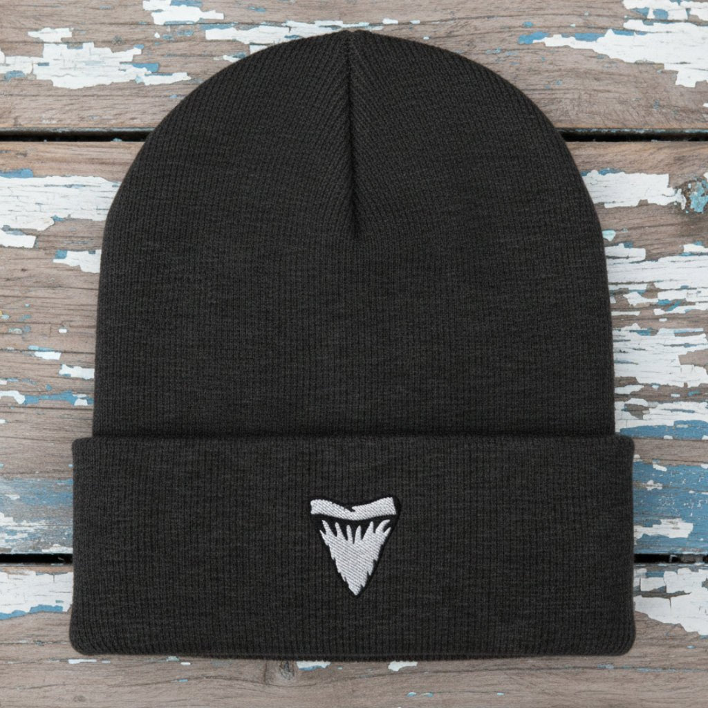 A dark charcoal gray ribbed knit beanie hat featuring a small white embroidered shark tooth logo on the front of the folded cuff, shown against a plain white background.