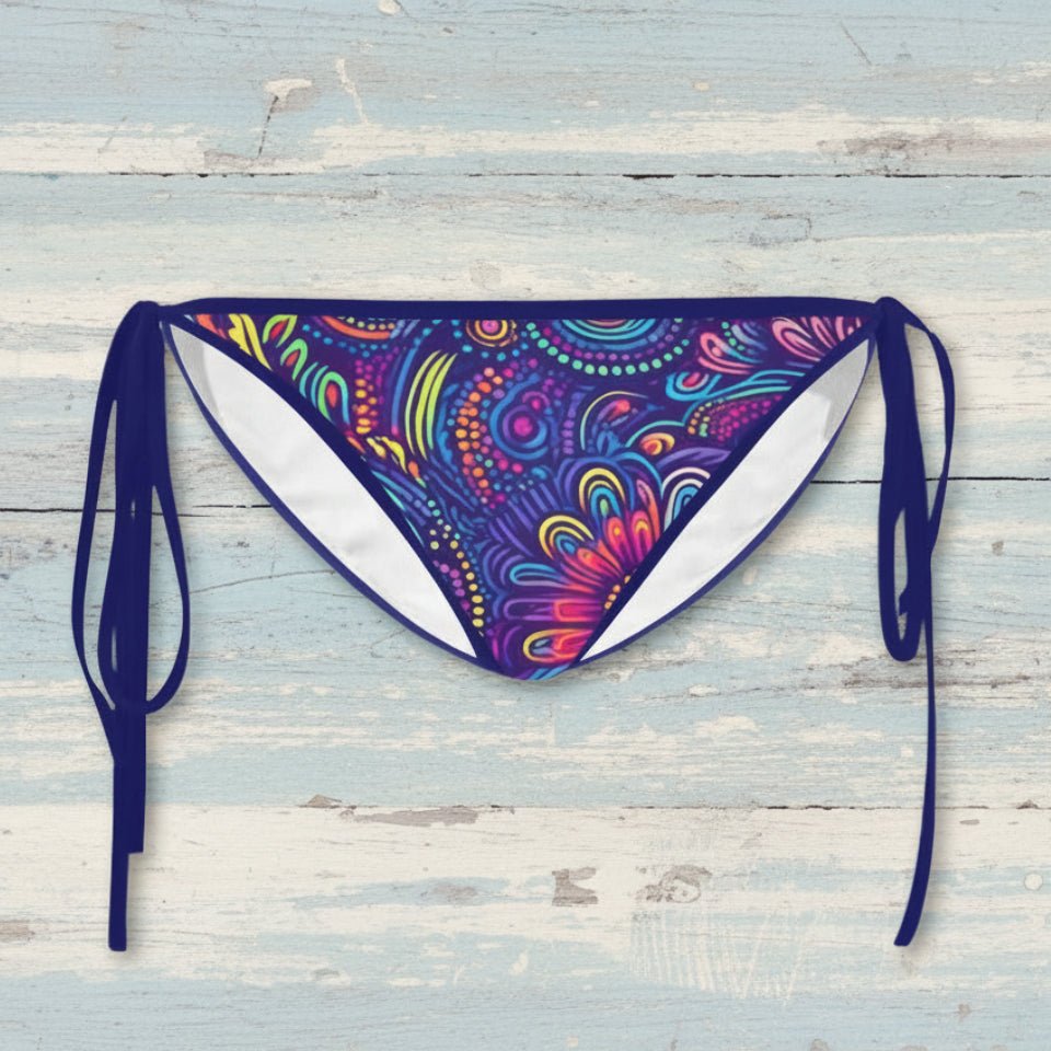 Colorful tribal patterned bikini bottom with blue straps on a rustic wood background