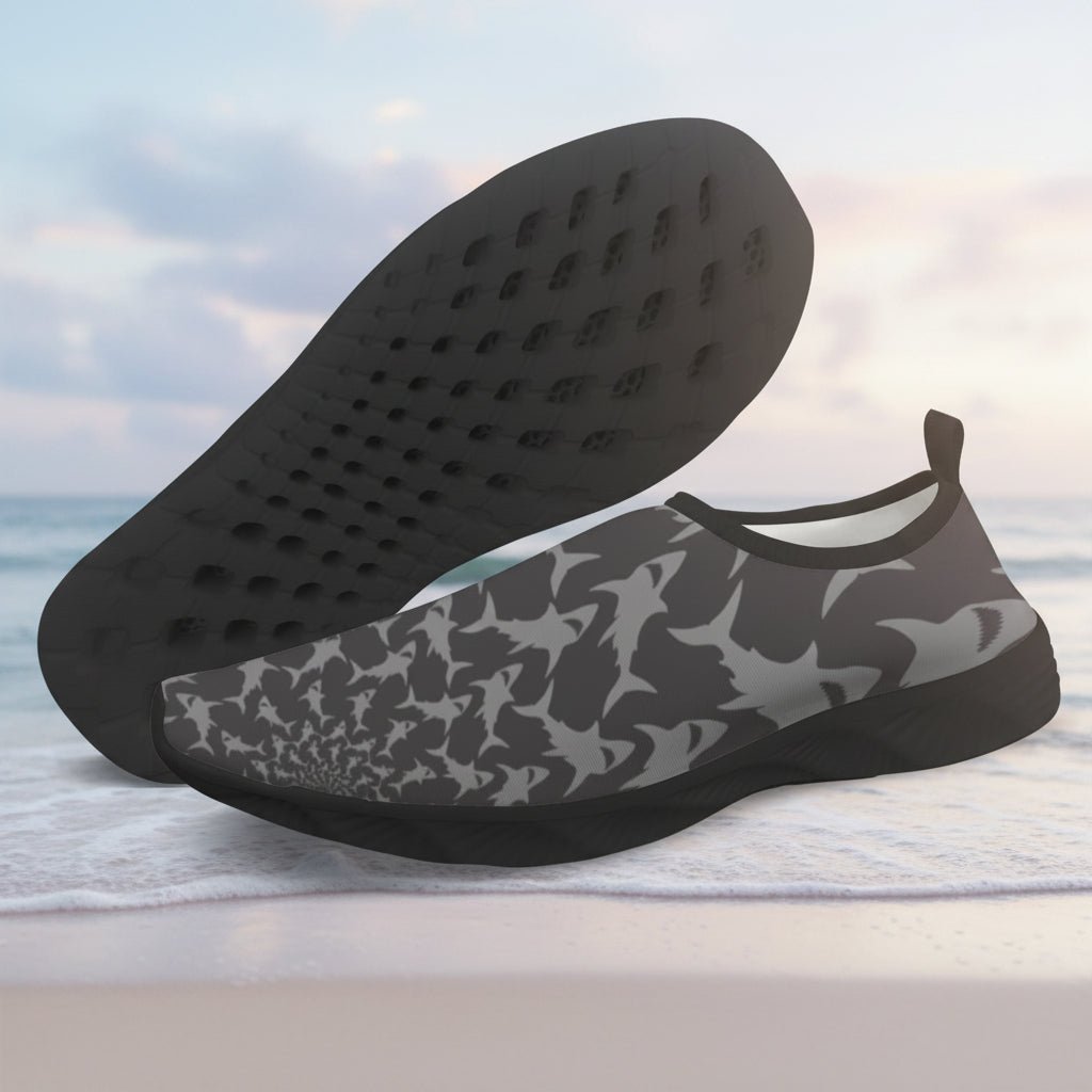 A pair of slip-on water shoes with a dark gray and black shark pattern on the upper, shown with one shoe displaying the textured black sole and the other showing the patterned upper, set against a plain white background.