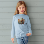 Child wearing a light blue sweatshirt with laughing tiki bongo design against a wooden nautical wall.