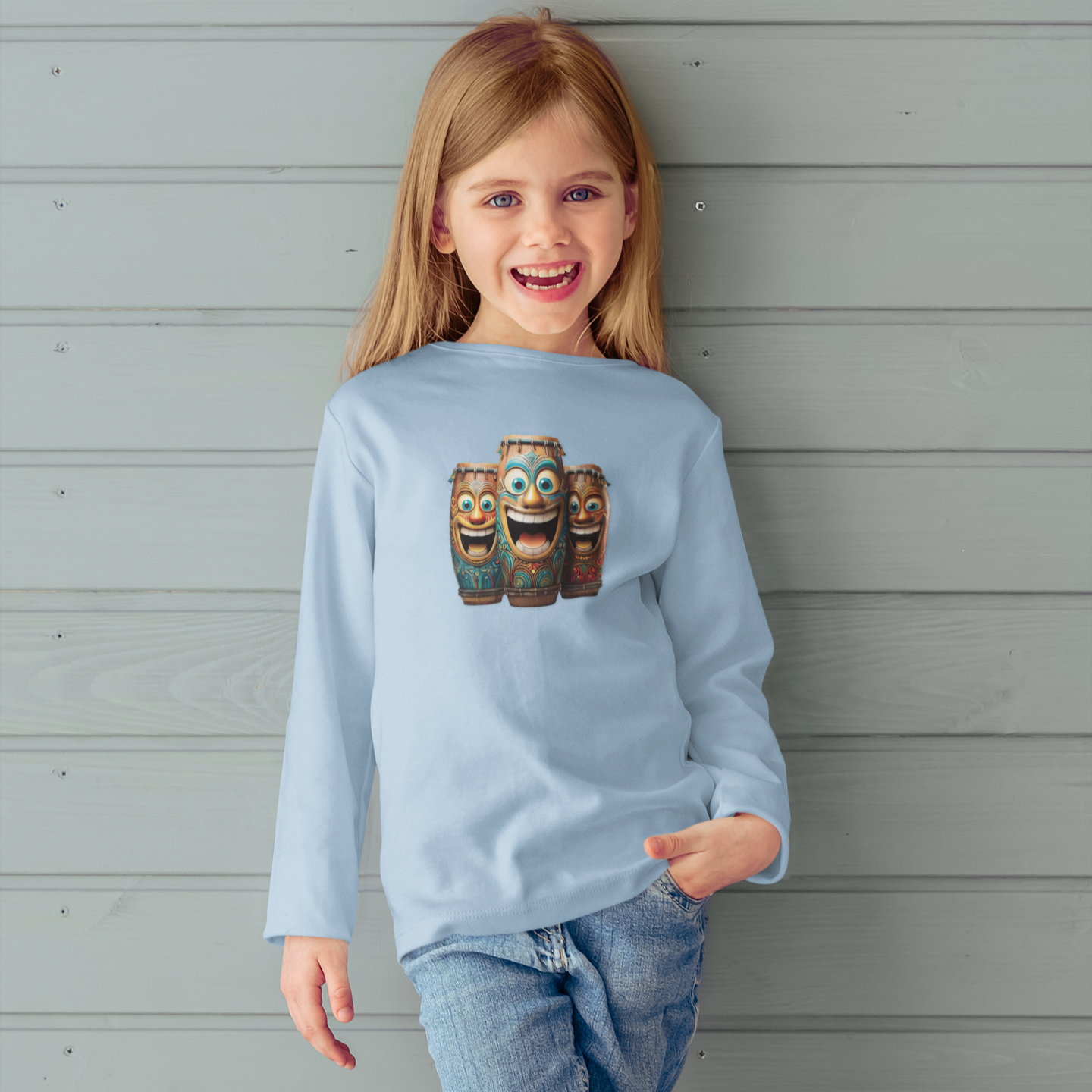 Child wearing a light blue sweatshirt with laughing tiki bongo design against a wooden nautical wall.
