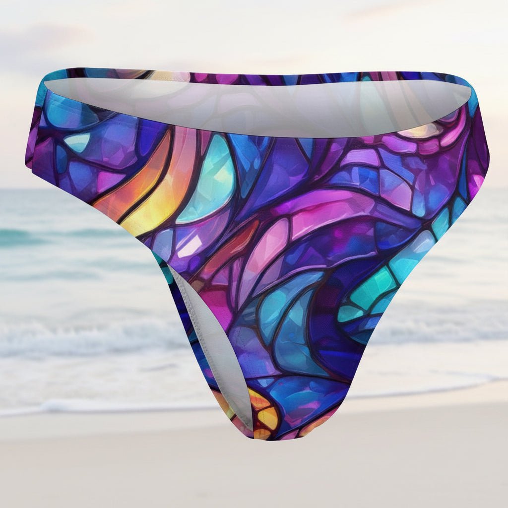 Colorful stained glass-patterned swim brief on a faded beach background