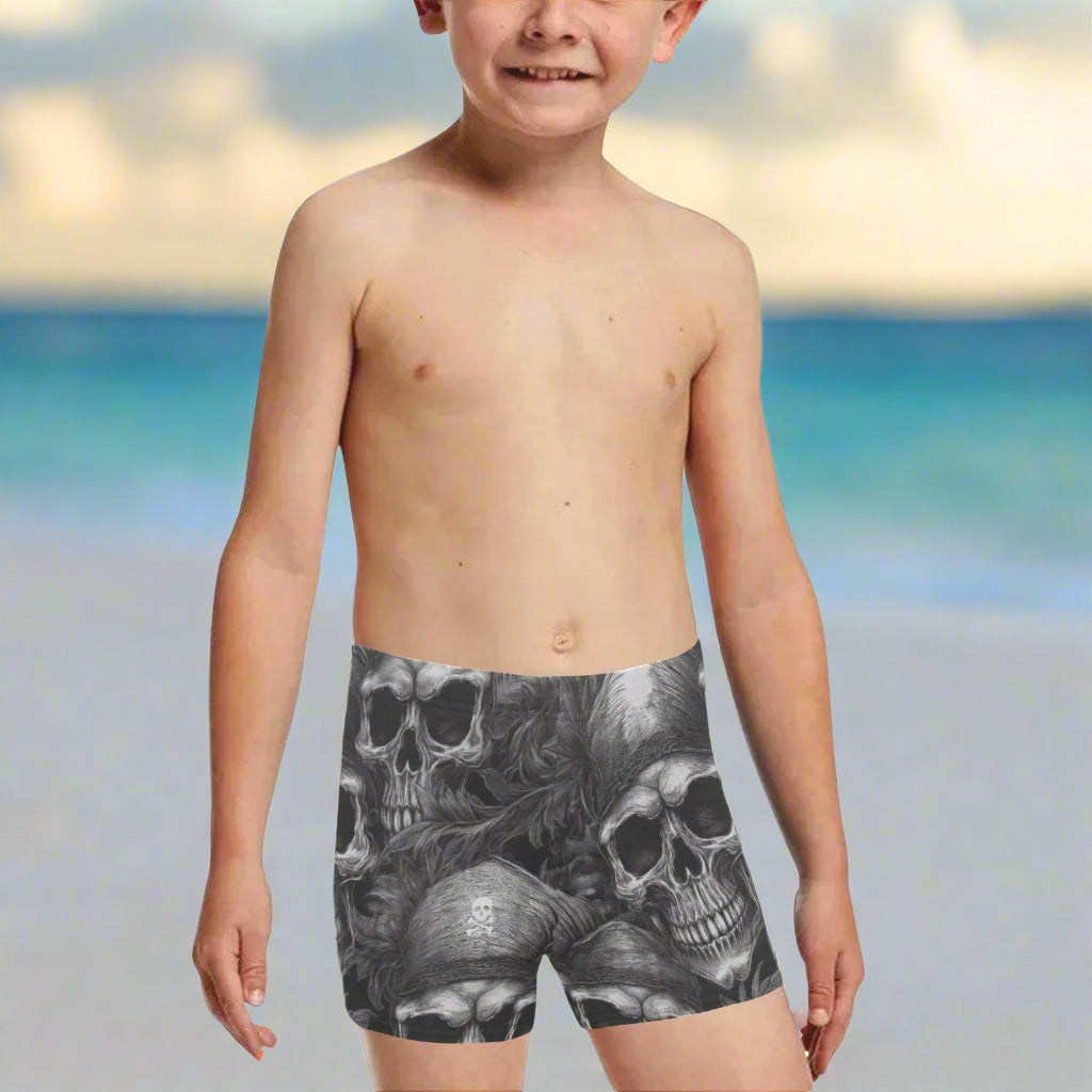 Boy wearing black and gray skull-patterned pirate skull swim shorts on a  Virgin Island beach
