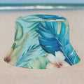 Bucket hat with tropical leaf and flower pattern on a white sandy beach