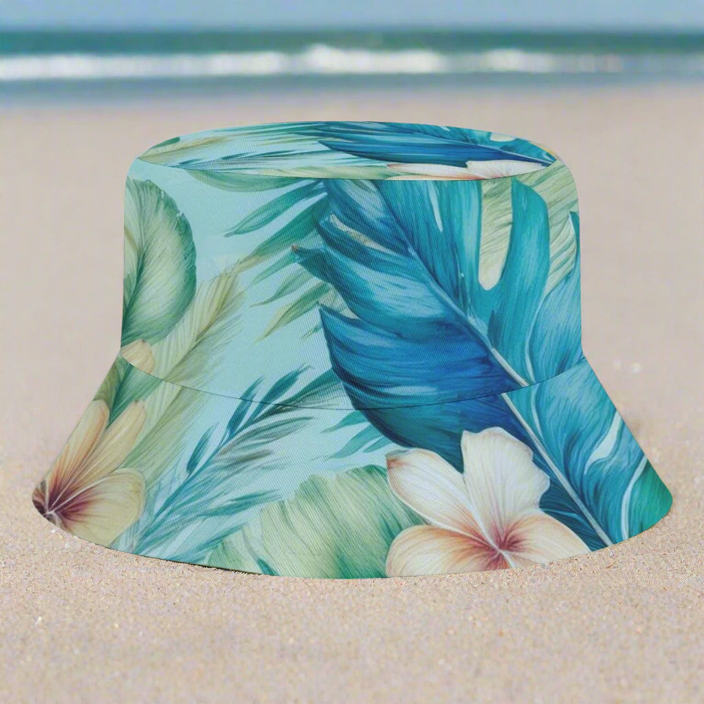 Bucket hat with tropical leaf and flower pattern on a white sandy beach