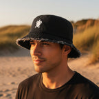 Dude wearing a dark navy denim bucket hat with a distressed frayed brim and a white embroidered sea turtle on the front. 