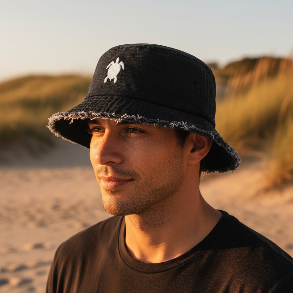 Dude wearing a dark navy denim bucket hat with a distressed frayed brim and a white embroidered sea turtle on the front. 