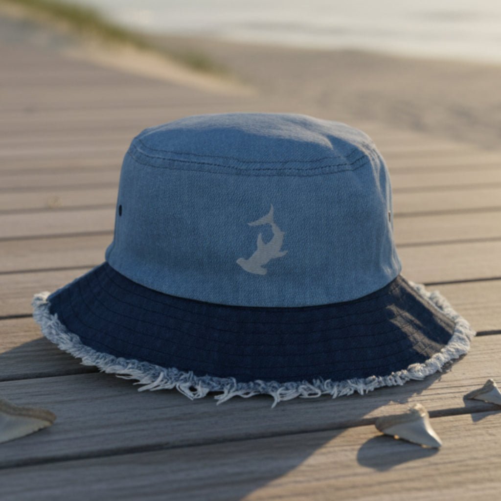 Blue bucket hat with a gray Hammerhead Shark embroidery on a beachside boardwalk