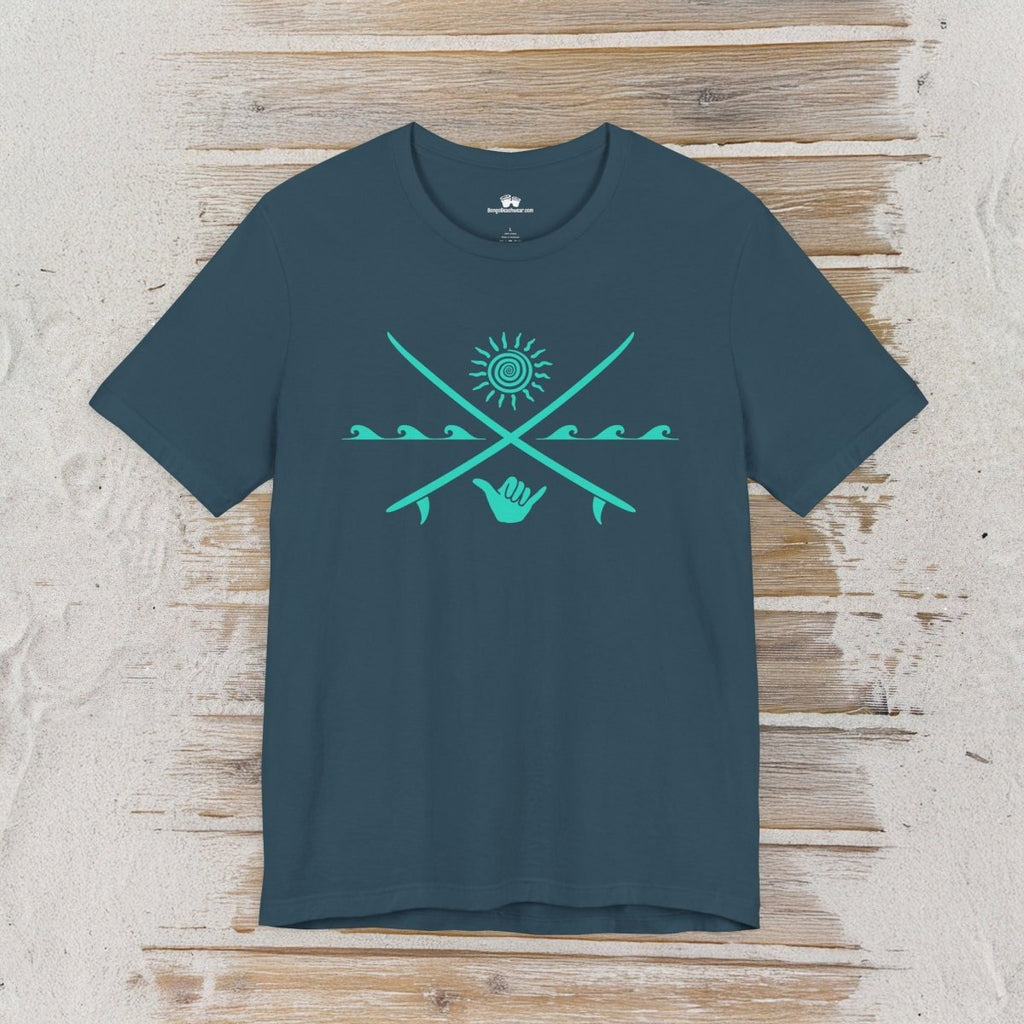 A dark teal crewneck t-shirt with a turquoise graphic of crossed fishing rods, a sun, and a hand symbol, displayed flat on a light wood plank background.
