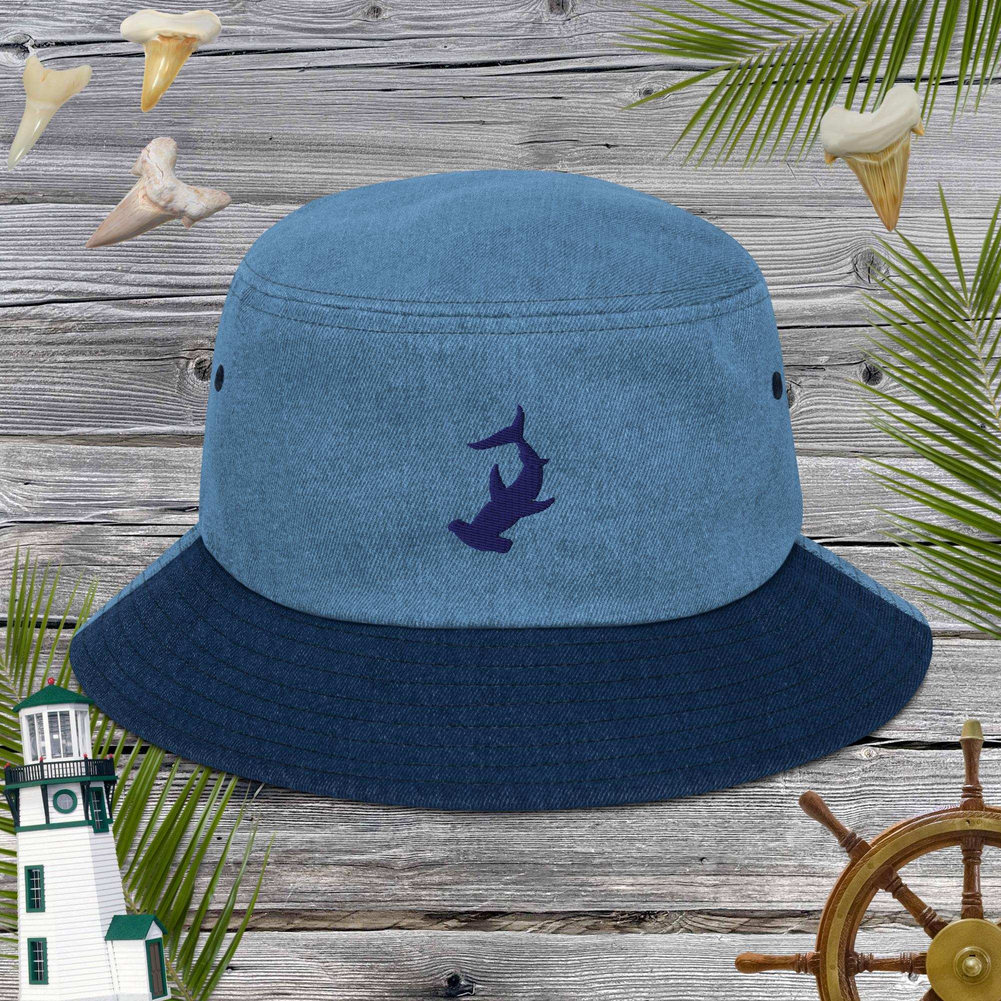 Blue bucket hat with hammerhead shark embroidery on a wooden background with nautical elements.