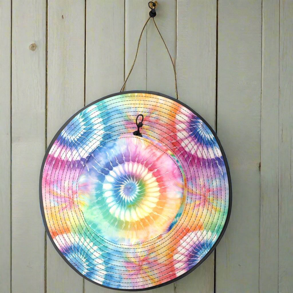 Colorful tie-dye bucket hat hanging by its drawstring chinstrap on a nautical wall