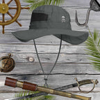 Gray sun hat with skull embroidery on a wooden background with nautical items.