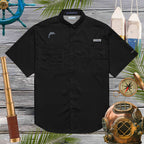 Black short-sleeve shirt with an embroidered dolphin logo on a wooden background with nautical decorations.