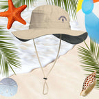 Beige bucket hat with a beachcomber logo on a beach-themed background with starfish, shells, and palm leaves.