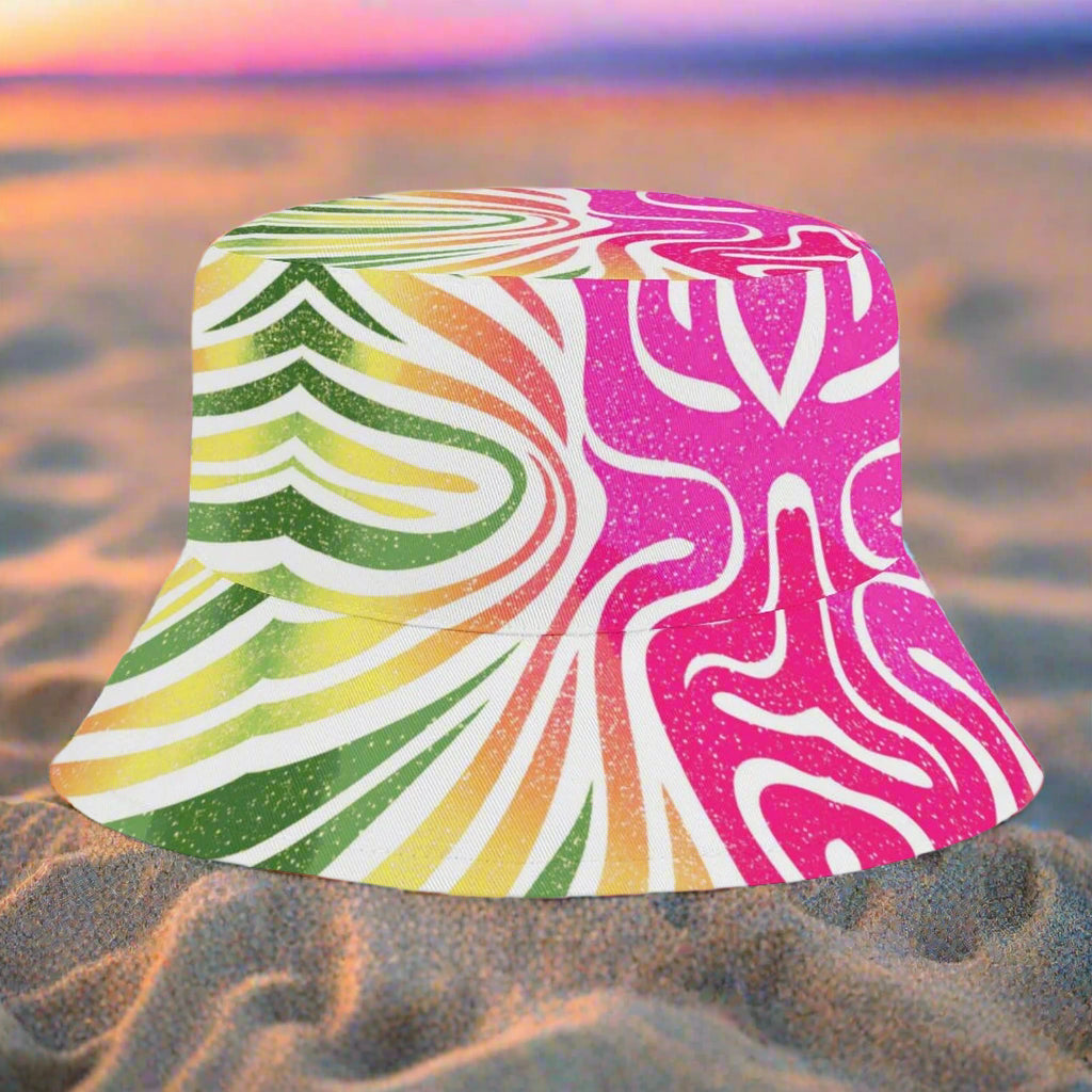 Colorful bucket hat with a vibrant, multicolored coral pattern sitting in the sand on a beach at sunset
