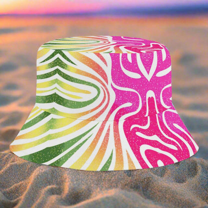 Colorful bucket hat with a vibrant, multicolored coral pattern sitting in the sand on a beach at sunset