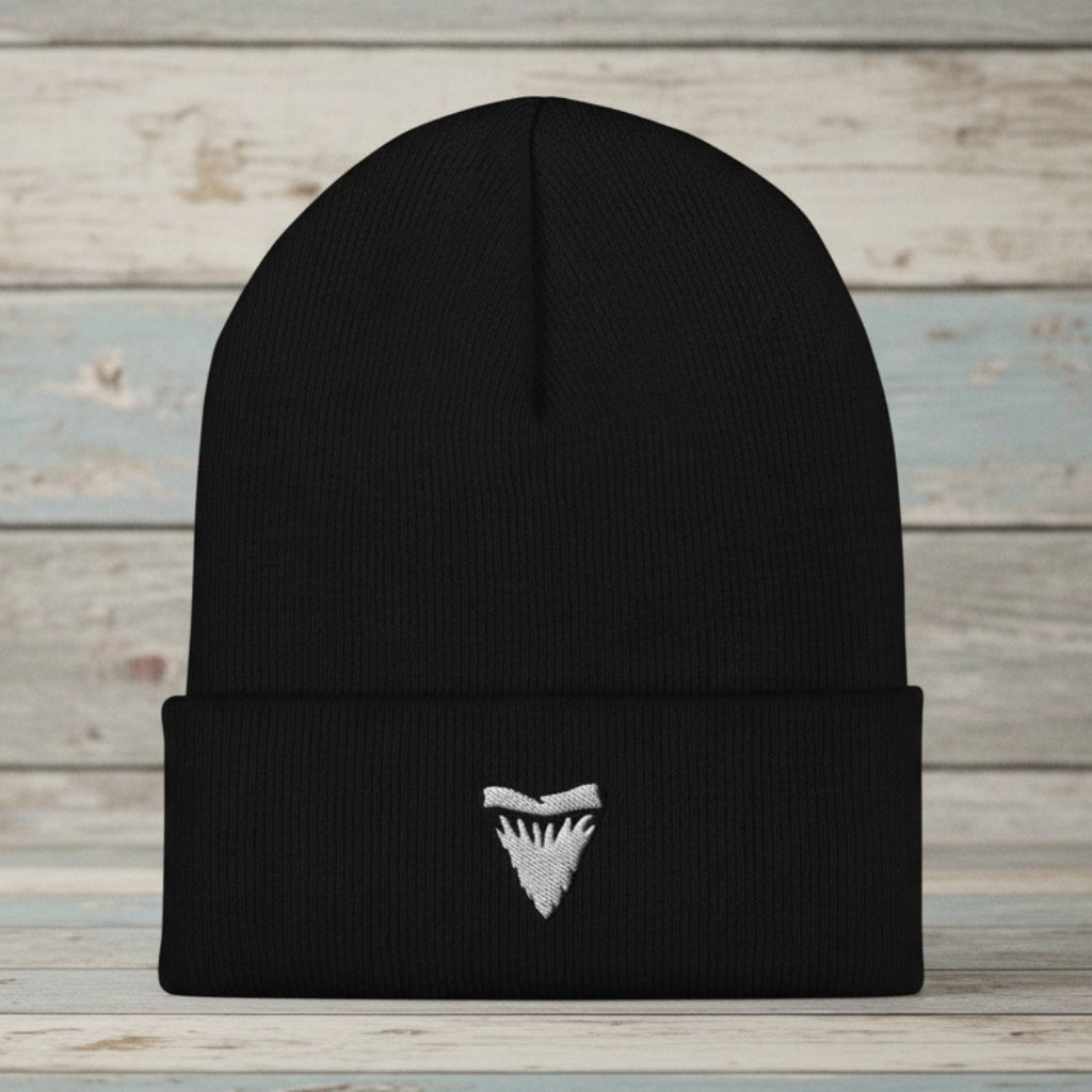 A black ribbed knit beanie hat with a folded cuff, featuring a small white embroidered shark tooth logo on the front, shown against a plain white background.