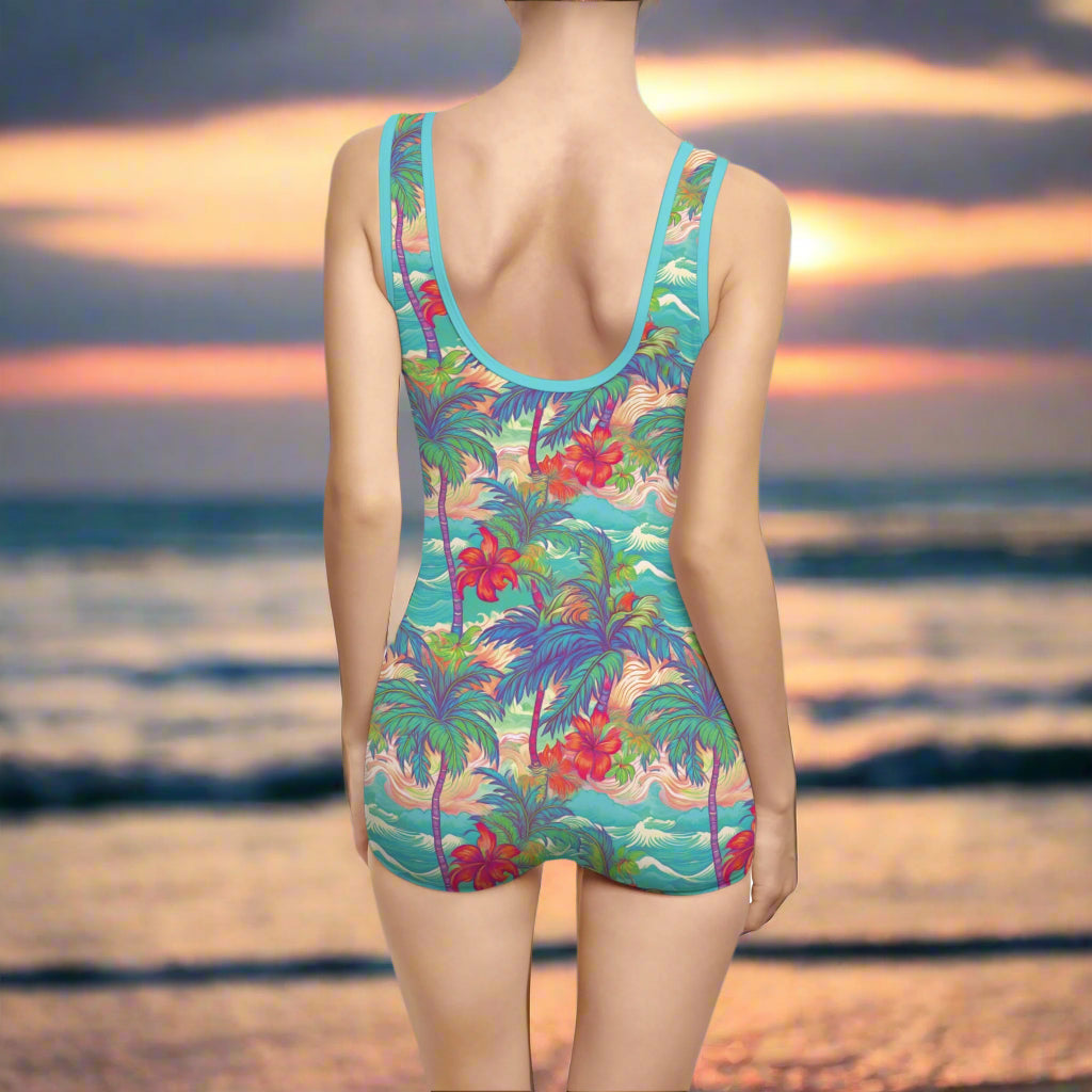 Woman wearing cute 1 piece bathing suit facing the ocean at sunset