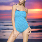 Model in Blue One Piece bathing suite with navy straps and a cool shark pattern is standing on the beach