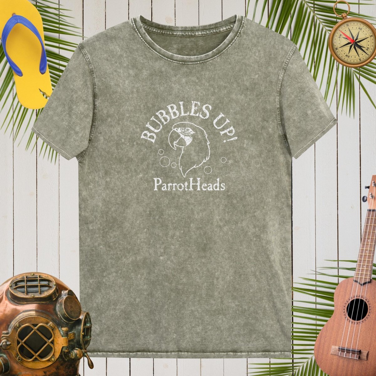 Gray t-shirt with 'Bubbles Up! ParrotHeads' design on a wooden background with tropical elements.