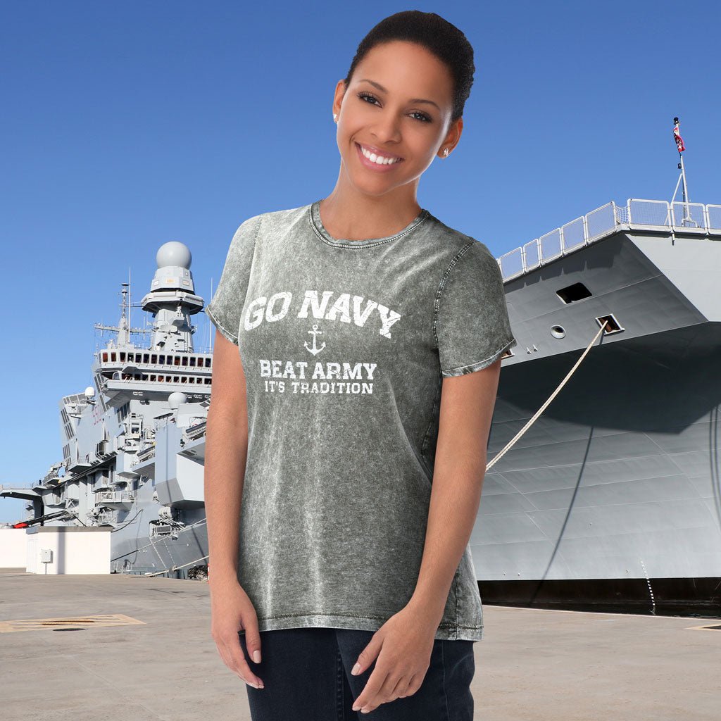 Woman wearing a 'Go Navy Beat Army' t-shirt in front of a large ship.