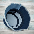 Blue denim bucket hat with frayed edges on a rustic wood background