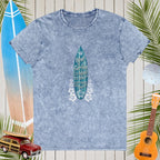 Blue t-shirt with a surfboard graphic and text on a wooden background with beach elements.
