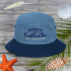 Blue bucket hat with text on a wooden surface with fishing-related items.