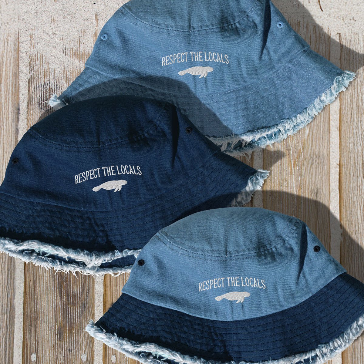 Three denim bucket hats with 'Respect the Locals' text on a wooden surface