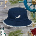 Navy blue bucket hat with shark design on a wooden surface with nautical decorations.
