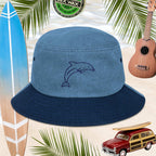 Blue denim bucket hat with dolphin embroidery on a beach-themed background with surfboard, ukulele, and model beach woody car.