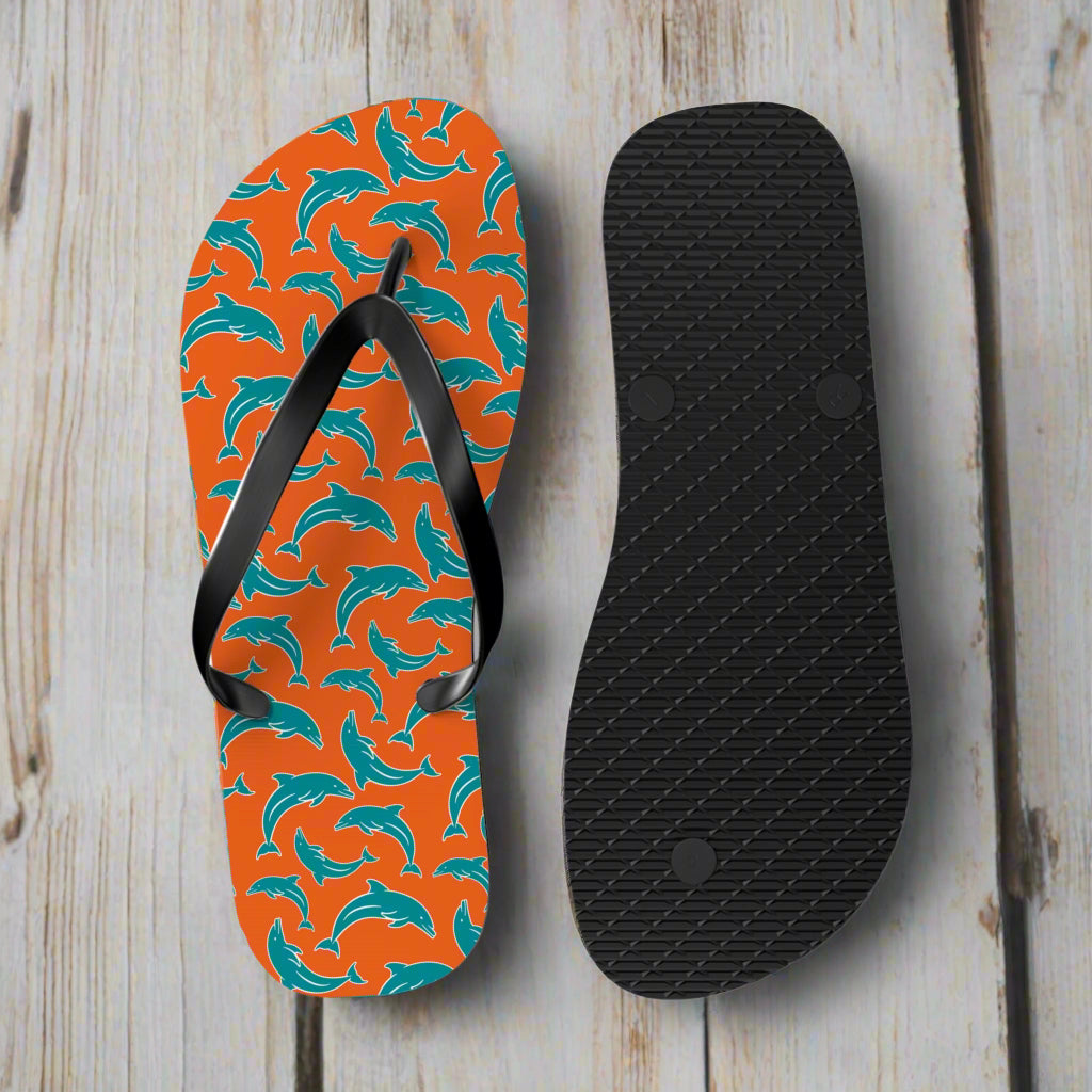 Flip-flops with pattern in dolphins team colors and black sole sitting on the deck of a vintage sailboat