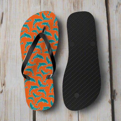 Flip-flops with pattern in dolphins team colors and black sole sitting on the deck of a vintage sailboat