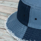 Close-up of a blue denim bucket hat with frayed edge on a nautical wood surface