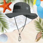 Gray sun hat with a strap and embroidered sea turtle on a beach background with sea, shell, and palm leaves.
