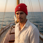 Sailor wearing a red knit beanie hat with a folded cuff, featuring a white embroidered palm tree