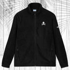 A black fleece zip-up jacket with a stand collar, shown flat against a white wood plank background with a palm leaf pattern overlay. The jacket features a small white circular logo on the left chest and a small white logo on the right sleeve.