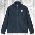 A dark navy blue fleece jacket with a full-zip front, stand-up collar, and zippered hand pockets, laid flat on a white wood plank background with a palm leaf pattern overlay.