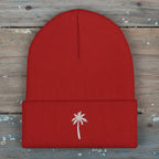 Red beanie with a white palm tree emblem on a rustic wood background