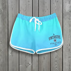 Light blue athletic shorts with a Fintastic Athletics logo on a rustic wood background