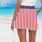 Person wearing a red, white, and blue striped board shotrs on a beach.