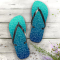Pair of blue flip flops with dolphin pattern on a wooden surface