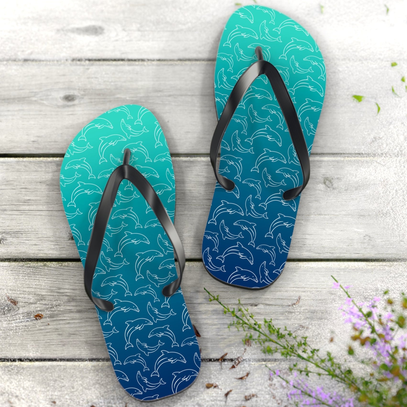 Pair of blue flip-flops with dolphin pattern on a wooden surface