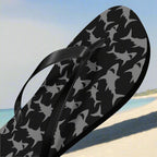 Black flip-flop with shark pattern on a beach background