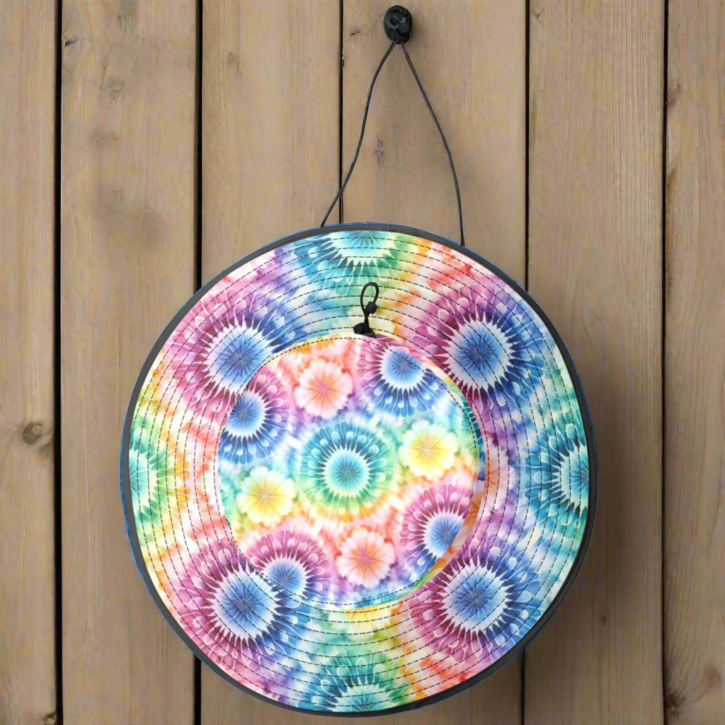 Colorful tie-dye patterned floppy beach hat hanging by a drawstring in a beachside cafe
